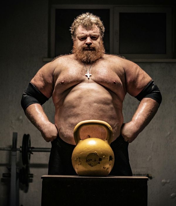 Man performing a powerful bodyweight exercise in a dark room.